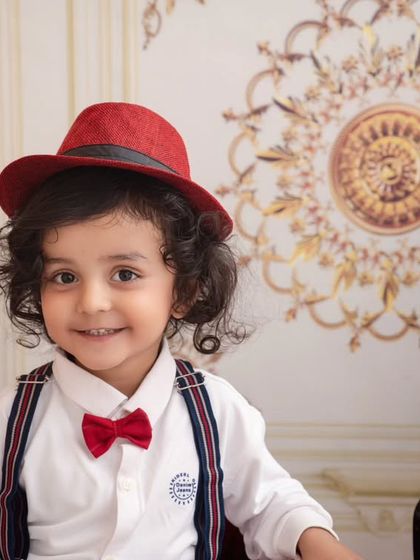 A handsome little musician with a charming smile, looking dapper in his bow tie and red hat.