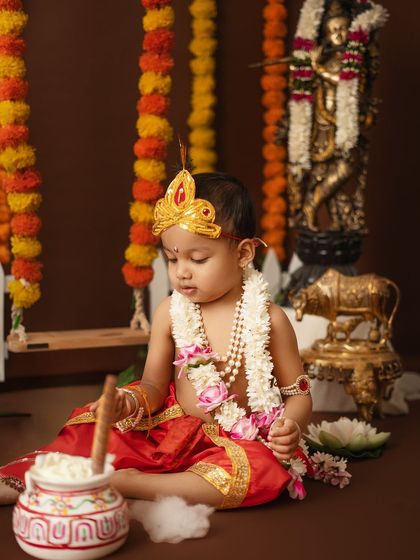 A quiet moment of a toddler as Krishna, curiously inspecting his pot of butter.