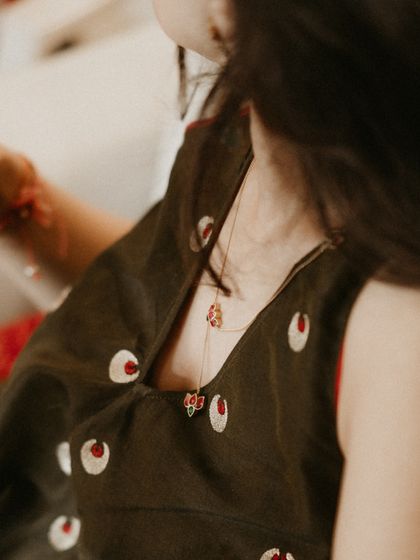 A detail shot of the bride's mehendi outfit, focusing on a delicate necklace against the unique fabric of her dress. We believe in curating indie feels and homegrown labels for a personal touch.