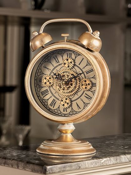 A masterpiece of design, this table clock blends old-world charm with modern engineering. The classic alarm clock shape is elevated with a vintage gold finish and a mesmerizing moving gear face.