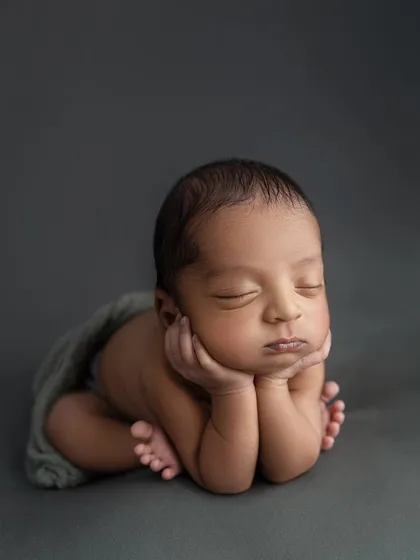 The 'chin on hands' pose is a favorite for a reason. It perfectly showcases the sweet, chubby cheeks and peaceful sleep of a newborn. Every detail is perfected to create a flawless, classic portrait.
