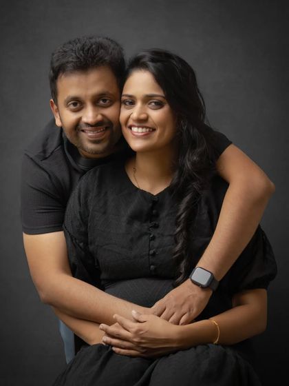 A classic black and white couple's portrait. The dark, moody background and close embrace create an intimate and timeless feel for this maternity moment.