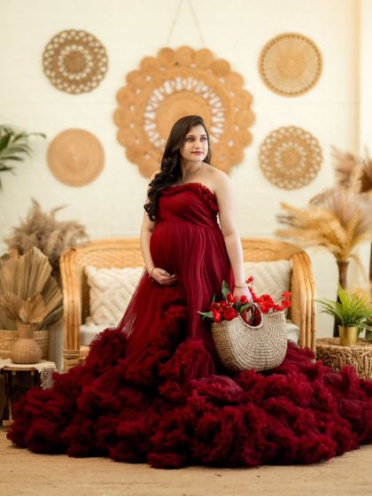 A lovely portrait of the mom-to-be holding a basket of red flowers, perfectly complementing her gown.