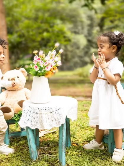 A candid and joyful moment between twins during their outdoor second birthday shoot, set up as a sweet teddy bear picnic.