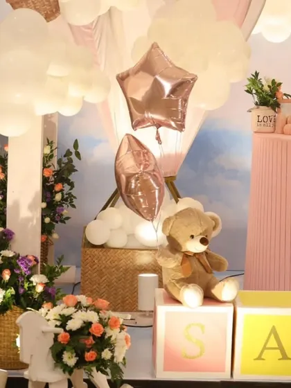 A close-up shot showing the details, including a teddy bear sitting on the personalized name blocks and star-shaped foil balloons.