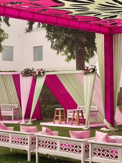 A seating area with alternating pink and mint green drapes, creating a fresh and vibrant look for a daytime Mehendi.