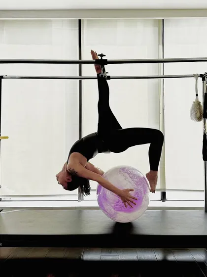 A stunning backbend over the stability ball while suspended on the Cadillac. This advanced move requires a high level of trust, strength, and flexibility.