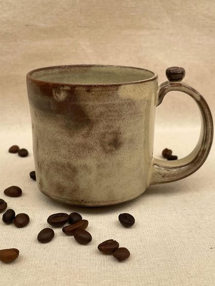 A collection of my handmade ceramic mugs, each with its own unique shape and glaze. The little coffee bean detail on the handle is a fun touch for coffee lovers.