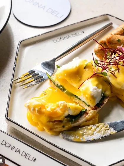 A classic eggs benedict, cut open to show the perfectly runny yolk. This is the ultimate "money shot" for any brunch menu.