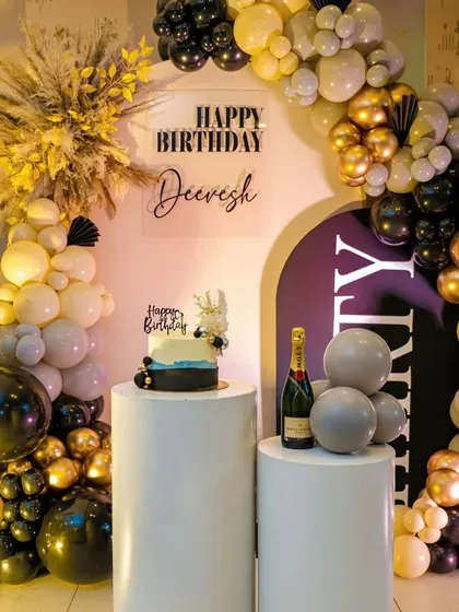 This is a perfect example of a sophisticated birthday setup for an adult. I used a classic black, gold, and white color scheme with a modern arched backdrop, a custom acrylic sign, and elegant white pedestals for the cake and champagne. The dried pampas grass adds a trendy, textural element.
