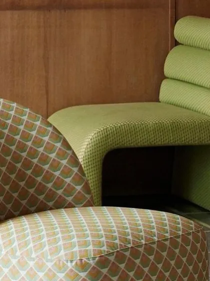 A close-up view of two uniquely designed chairs, one featuring a bold geometric pattern and the other a vibrant solid green with a ribbed back. This image showcases our range in custom upholstery, from playful patterns to sculptural, modern forms.