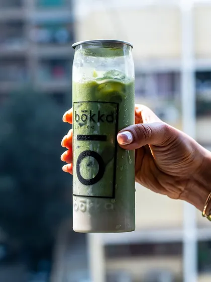 A lifestyle shot of the canned matcha latte held up against a city background. This connects the product to the urban, on-the-go consumer.