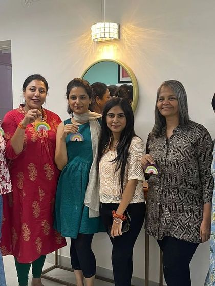 A group of friends proudly holding up the rainbow charms they made during a fun-filled workshop session.