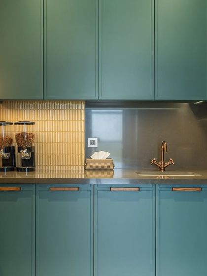 A close-up of the kitchen's custom teal cabinetry and gold-tiled backsplash. We pay close attention to details like hardware and task lighting to ensure the kitchen is as beautiful as it is practical.