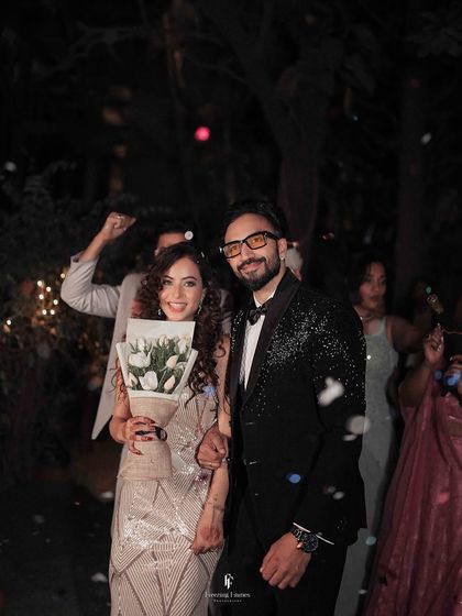 A joyful, candid shot of the couple during their reception entrance, surrounded by confetti and cheering guests.