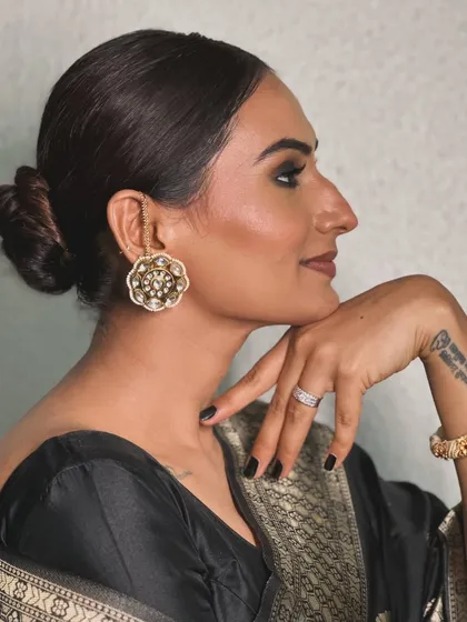 A side profile showcasing the sleek bun and bold makeup.