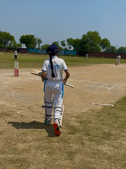 A lone batswoman walks to the crease, focused and determined.