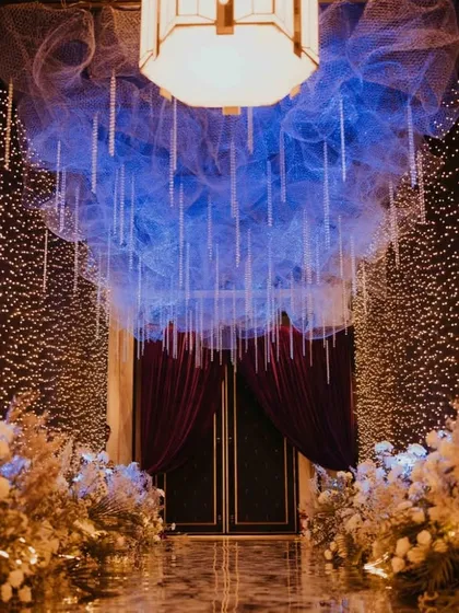 A closer view of the starry sangeet entrance. The ceiling is a cloud of blue mesh with hanging crystal strings, while the walls are covered in a dense curtain of warm fairy lights, creating a breathtaking and immersive experience.