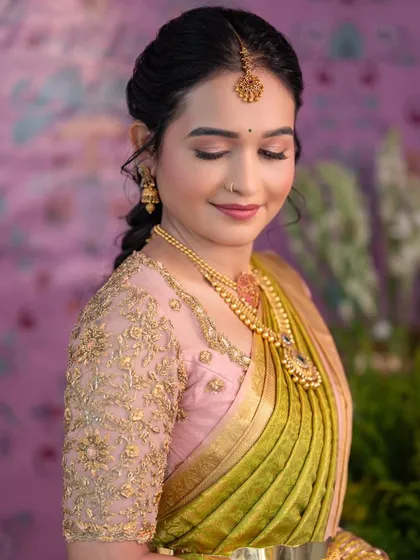 A close-up of the bride's pink blouse with sheer, embroidered sleeves. This detail adds a contemporary and delicate feel to her traditional bridal attire.