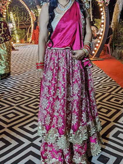 A beautiful double-layer gher lehenga in a vibrant pink, perfect for a wedding guest. This rental piece ensures you have a grand look for the event.