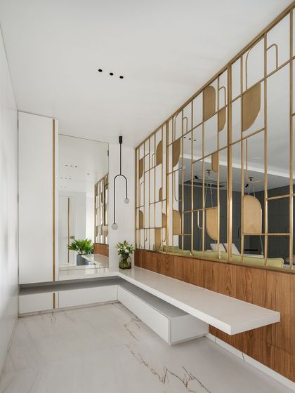 The foyer sets the tone for the entire home. I designed this entrance with a custom brass partition that creates an artistic statement while separating the entryway from the formal living area. The floating bench and full-length mirror add both function and a sense of spaciousness.