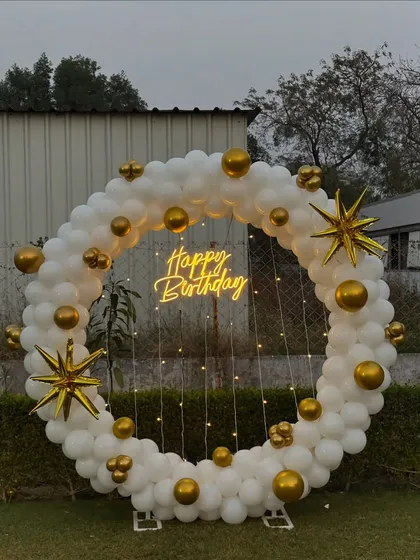 A slightly different angle of the white and gold outdoor ring, with star-shaped foil balloons and fairy lights.