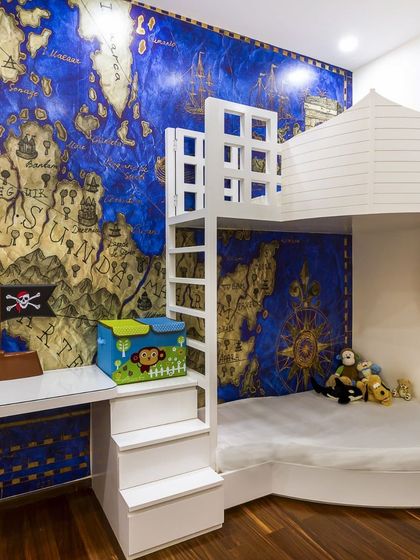 A room to spark imagination! This pirate-themed kids' room features a custom bunk bed with stair storage and a stunning world map mural. It's a space for adventure and dreams.