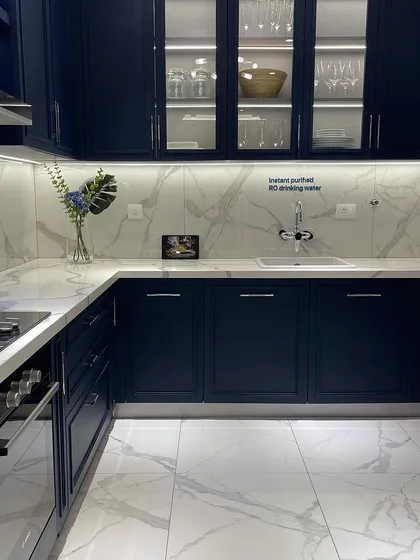 This modern kitchen features sleek navy cabinetry, marble patterned surfaces, and integrated lighting. It's a perfect example of the curated, high end interiors I look for in a property.
