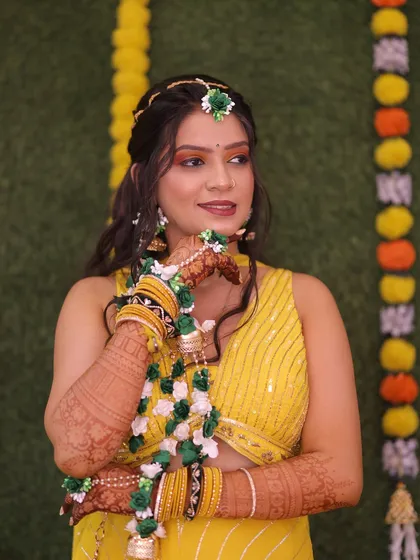 A candid shot of the Haldi bride. The makeup is kept fresh and glowing, with a focus on waterproof products to withstand the playful nature of the ceremony.