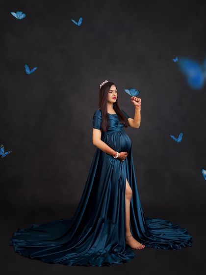 A whimsical portrait with blue butterflies seemingly fluttering around the mom-to-be in her beautiful teal gown.
