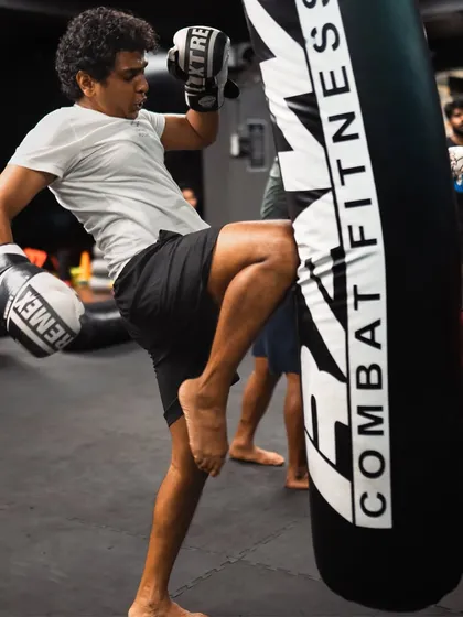 A student practices a knee strike on the heavy bag, building power and proper form.
