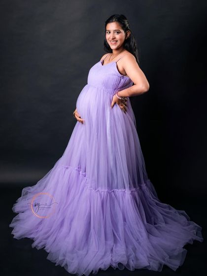 A happy and confident solo portrait. The mom-to-be's joyful expression and the beautiful lavender gown make for a stunning combination.