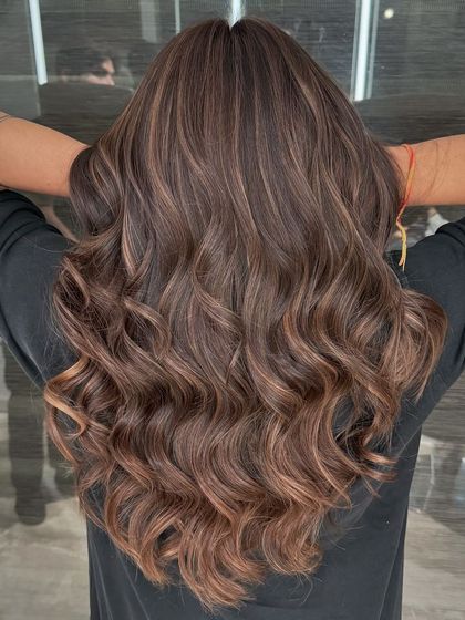 The back view of our Chestnut Brown balayage. You can see how the light catches the different tones, creating beautiful dimension and movement in her wavy hair.