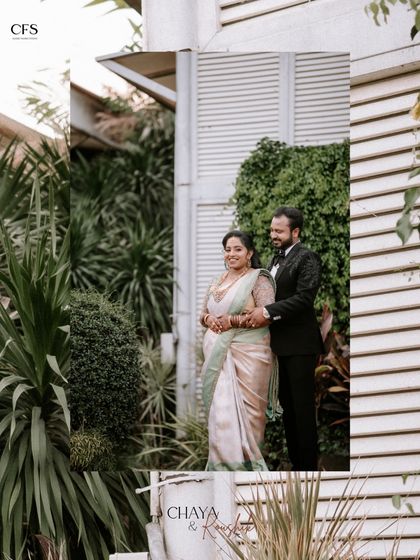 A classic reception portrait set against a lush green wall. The bride's elegant saree and the groom's sharp tuxedo make for a timeless and sophisticated wedding photograph.