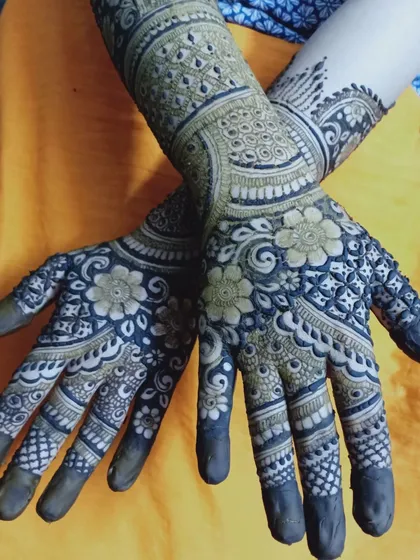 A full view of the hands, where the intricate palm design is complemented by simpler, elegant bands on the forearms.