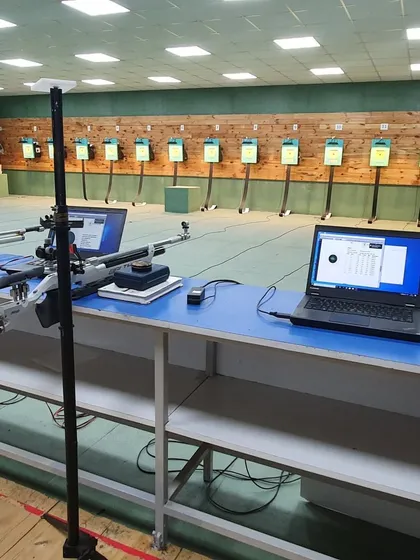 A view of the firing line prepared for a competition. Each lane is equipped with a laptop connected to an electronic target system for precise, real time scoring.