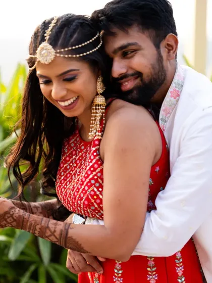 A sweet, candid hug during the Mehendi. The bride's intricate henna and her happy smile are the focus of this lovely shot.