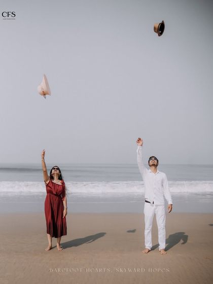 A fun, carefree moment as the couple throws their hats in the air on the beach. This shot captures a sense of freedom and joy.