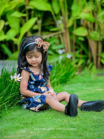 A quiet, contemplative moment captured in a garden. This toddler is sitting peacefully on the grass, creating a serene and beautiful portrait.