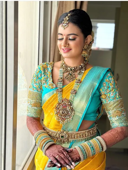 The beauty of 92.5 silver-based jewellery is unmatched. This grand bridal set, with its intricate craftsmanship and pearl detailing, looks absolutely radiant against the vibrant yellow and turquoise Kanjeevaram saree.