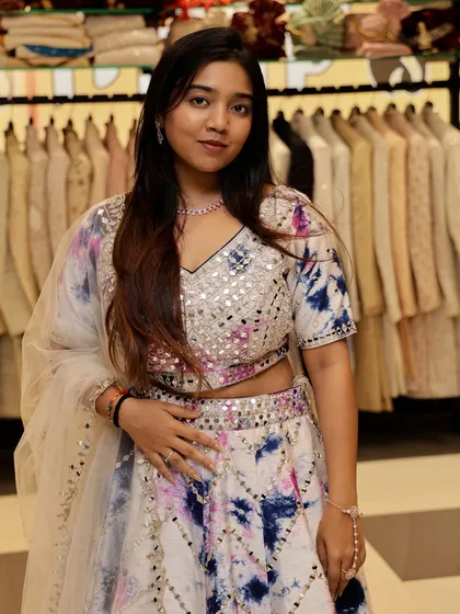 A close-up of the white tie-dye lehenga, showing the vibrant colors and sparkling mirror work.