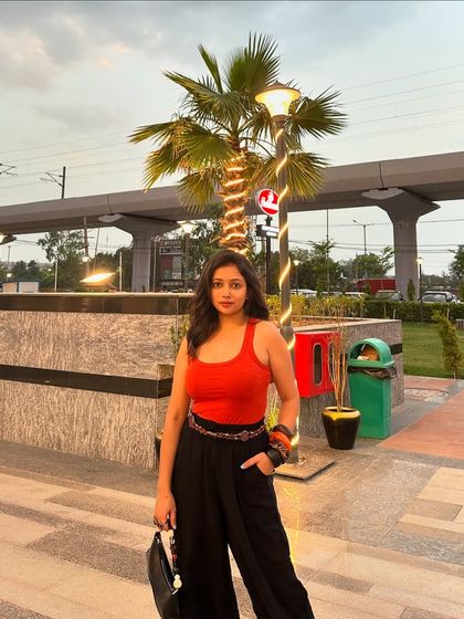An evening look featuring a bright orange tank top and black dhoti-style pants. The contrast is striking and chic, perfect for a casual dinner or outing.