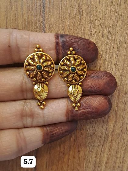 A pair of antique gold-plated earrings with a sun-like floral design and a central black stone. They are a unique and eye-catching choice.