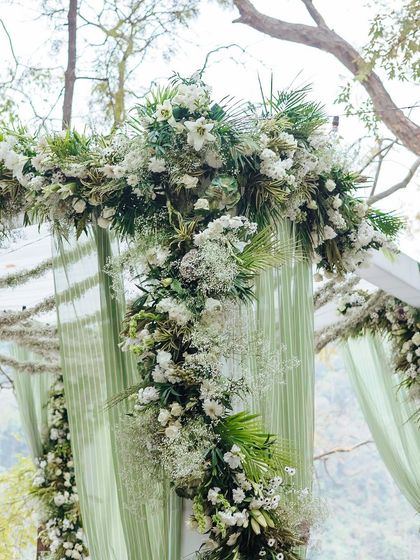 A close-up of the intricate floral arch of the mandap, featuring a mix of white flowers and green foliage.