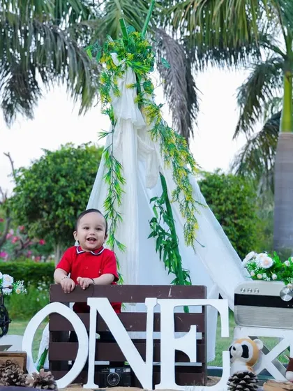 A wide shot of our outdoor setup for a first birthday, featuring a teepee, the number "ONE," and lots of fun props in a beautiful park.