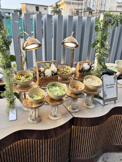 A rustic-chic salad bar setup with wooden stands and warm lighting. This inviting display encourages guests to create their own healthy and delicious salads, adding an interactive element to the meal.