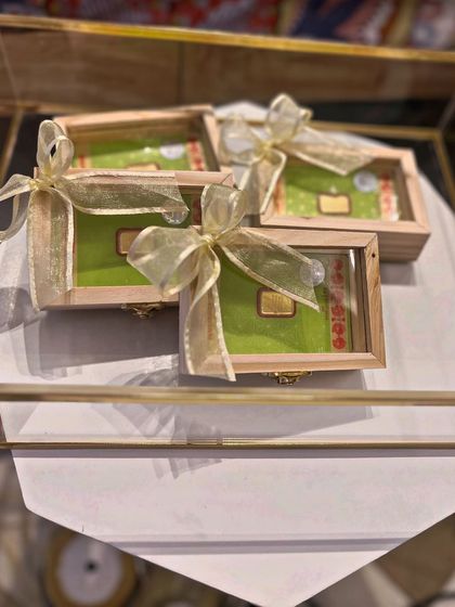 Even the smallest gifts, like these gold coins, are presented with care. The wooden boxes with glass lids are tied with a simple gold ribbon, fitting perfectly within the luxurious and earthy Moroccan aesthetic.