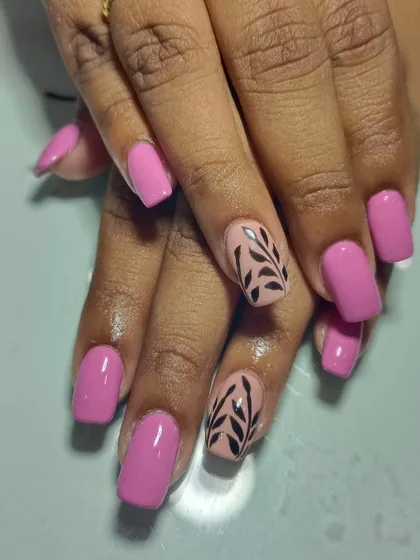 Pink nails are always in fashion. These gel extensions feature a solid pink with a contrasting nude accent nail and black leaf pattern.