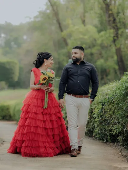 A romantic walk through a wooded area in Pune. The woman's flowing red gown creates a beautiful contrast with the natural greenery, resulting in a cinematic shot that feels both grand and intimate.