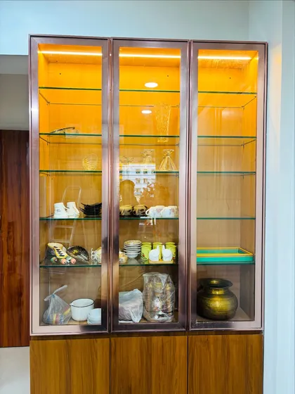 A frontal view of the crockery unit, emphasizing the warm lighting and the ample storage space provided by the glass shelves.